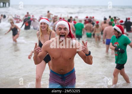 Swimmers take part in the Macmillan Boscombe White Christmas Dip, in aid of Macmillan Caring Locally, at Boscombe Pier, Bournemouth, Dorset. Picture date: Sunday December 25, 2022. Stock Photo