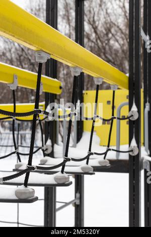 suspension bridge on the playground in winter close-up. suspension bridge covered with snow. suspension bridge. Stock Photo