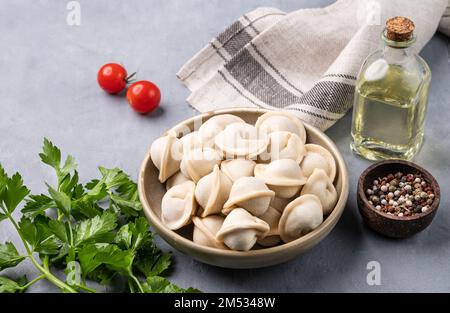 Dumplings with meat. The Russian traditional dish is Siberian pelmeni. Served with fresh herbs, butter and vegetables close up. Stock Photo