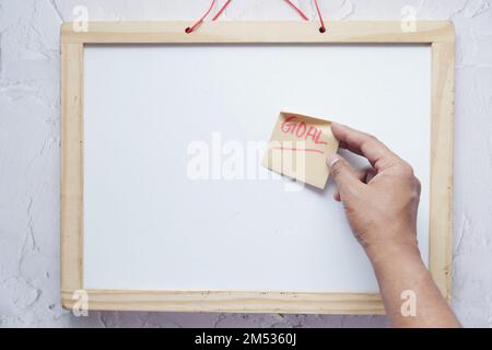 putting a new year goals sticky note on a white board  Stock Photo