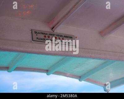 Please wear the life jacket sign on the boat in English, Malay and Chinese languages. Stock Photo
