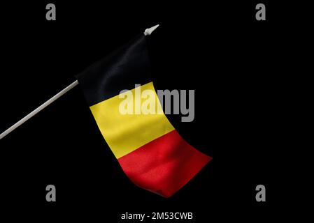 The flag of Belgium on a black background is developing and flying in the wind. Stock Photo