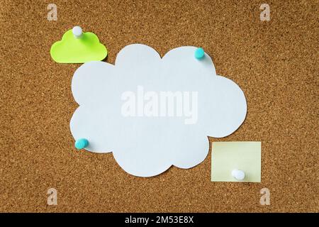 Colorful stickers pinned to a cork board close-up. Three sticky notes for text message. Big blank white cloud notepaper and two small yellow reminders. Stock Photo