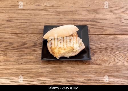 Typical Spanish tortilla sandwich on a square black porcelain plate Stock Photo