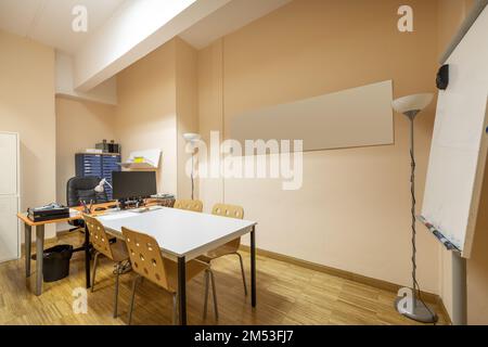 Work tables in an office with a blackboard of deleble markers Stock Photo