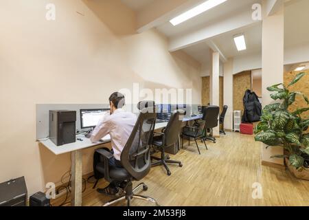 Workstations at a long table in an office with industrial oak parquet flooring Stock Photo
