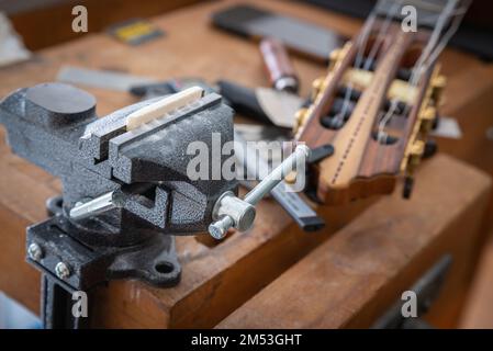 Musical instrument guitar repair and service - guitar bone nut slotting, placed in vice and slotted. Stock Photo