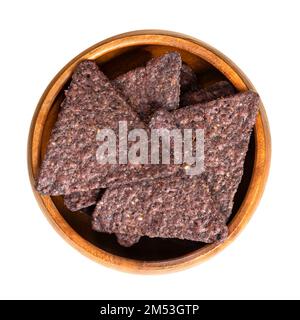 Blue tortilla chips, in a wooden bowl. Snack food, made from blue corn tortillas, cut into triangle shaped wedges, fried in oil and slightly salted. Stock Photo