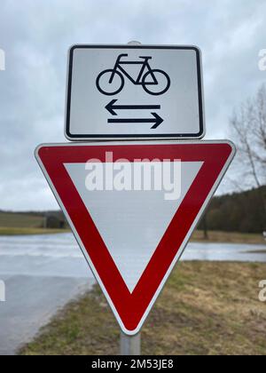 A vertical shot of the Yield and bicycle street signs seen by the side of the road Stock Photo