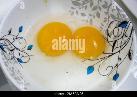 Two white and yellow yolk chicken eggs in a white bowl. Stock Photo