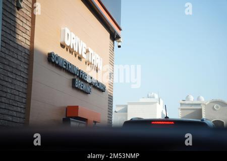 Dunkin doughnuts drive-thru sign with the slogan 'something fresh is always brewing' in the middle east in the morning. Stock Photo