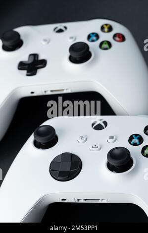 New york, USA - December 21, 2022: Two xbox controllers different generation on black studio background Stock Photo