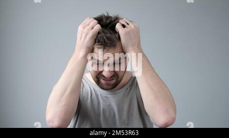 Young man is irritated, he is tearing the hair on his head in stress Stock Photo