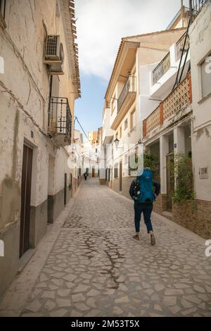 A vertical view of a tourist walking along a narrow street in Alcala del Jucar Stock Photo