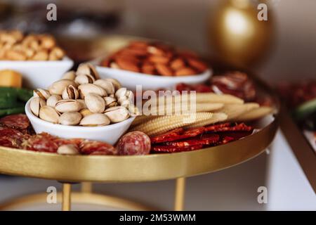 Appetizers platter with different antipasti, charcuterie, snacks, different types of nuts, cheese, vegetables. Finger food for buffet party. Tradition Stock Photo