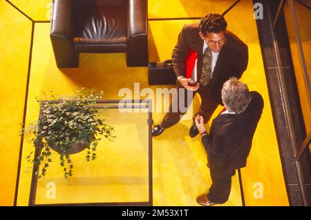 Overhead looked down of two businessmen in suits discussing business in an office environment Stock Photo