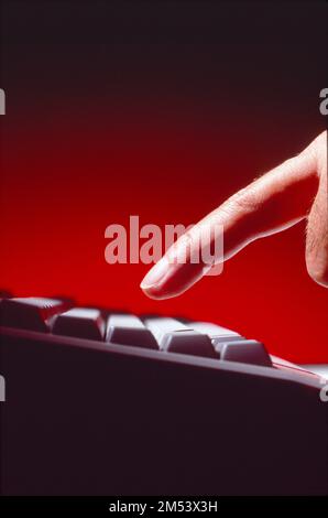Close-up shot of a single finger getting ready to touch the keyboard Stock Photo