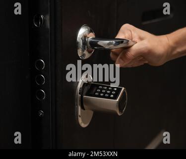 Woman opens the combination lock on the door to the apartment. Keyless entry.  Stock Photo