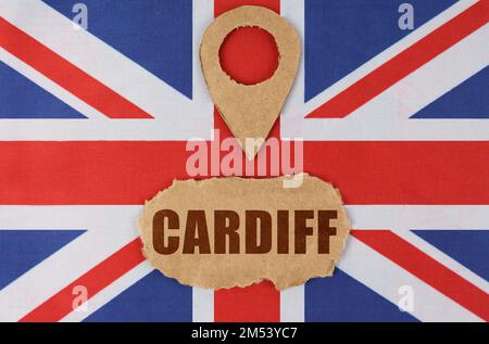 Travel concept. On the flag of Great Britain lies a symbol of geolocation and cardboard with the inscription - Cardiff Stock Photo