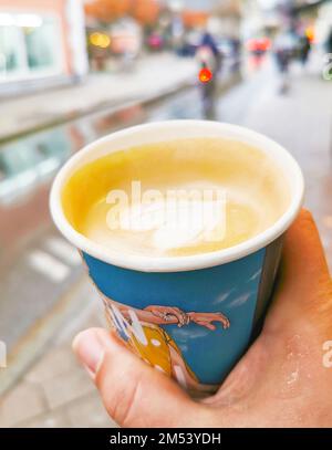 A woman's hand holds a color paper cup of hot coffee to go, take away, big city concept, stock photo Stock Photo