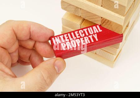 Business and technology concept. From the tower with wooden planks, they take out a red plaque with the inscription - Intellectual property Stock Photo