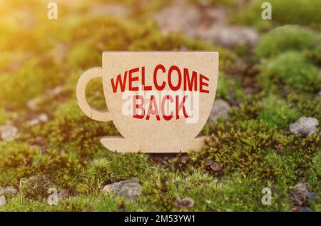 Business concept. On the moss in the rays of the sun, a cup with the inscription - Welcome back Stock Photo