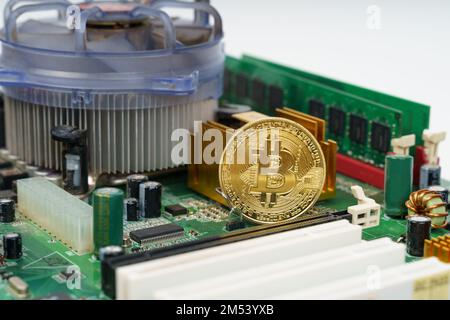 Business and technology concept. There is a golden bitcoin coin on the motherboard of the computer. Stock Photo