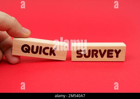 Business concept. On a red background, wooden blocks, one of them in hand. The blocks are written - QUICK SURVEY Stock Photo