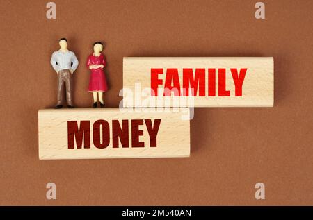 Business and people concept. On wooden blocks with the inscription - FAMILY MONEY, there are miniature figures of people. Stock Photo