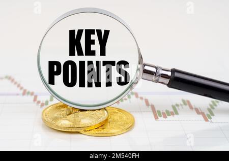 Business and technology concept. On the chart with quotes are bitcoins and there is a magnifying glass with the inscription - KEY POINTS Stock Photo