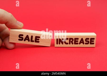 Business concept. On a red background, wooden blocks, one of them in hand. The blocks are written - SALE INCREASE Stock Photo