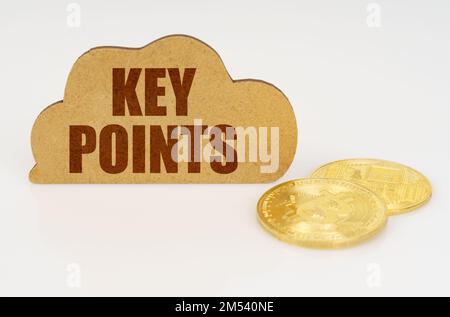 Business and technology concept. Bitcoins lie on a white surface and there is a sign - a cloud with the inscription - KEY POINTS Stock Photo