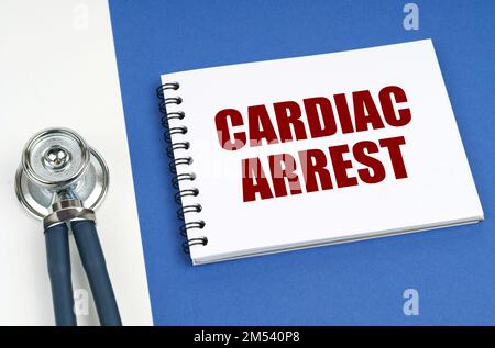 Medical concept. On a blue-white surface lies a stethoscope and a notepad with the inscription - CARDIAC ARREST Stock Photo