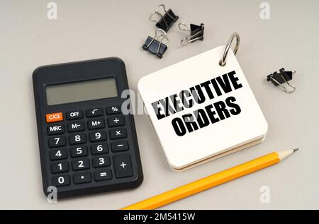 Business concept. On a gray surface, a calculator, a pencil and a notepad with the inscription - Executive Orders Stock Photo