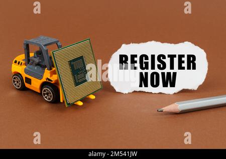 Technological concept. On a brown surface, a forklift is transporting a processor, next to it is paper with the inscription - register now Stock Photo