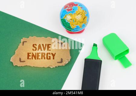 Ecological and industrial concept. On the table is a globe and a marker, on a green background there is a cardboard with the inscription - Save Energy Stock Photo