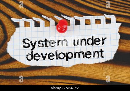 Business concept. Attached to the board is an announcement with the inscription - System under development Stock Photo