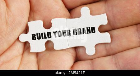 Business concept. In the hand of a man are puzzles with the inscription - Build Your Brand Stock Photo