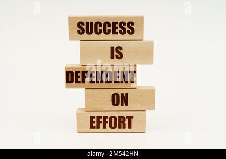 Business concept. On a white surface are wooden blocks with the inscription - SUCCESS IS DEPENDENT ON EFFORT Stock Photo