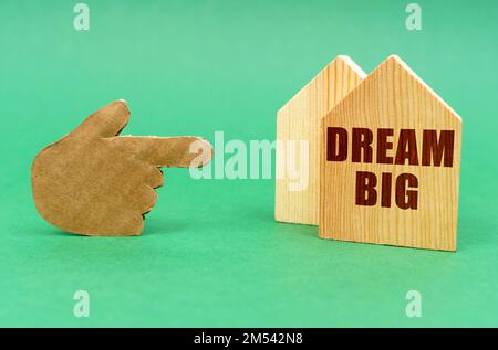 Business real estate concept. On a green surface, a hand points to a house with an inscription - Dream Big Stock Photo