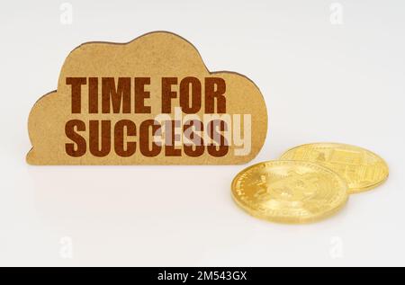 Business and technology concept. Bitcoins lie on a white surface and there is a sign - a cloud with the inscription - TIME FOR SUCCESS Stock Photo