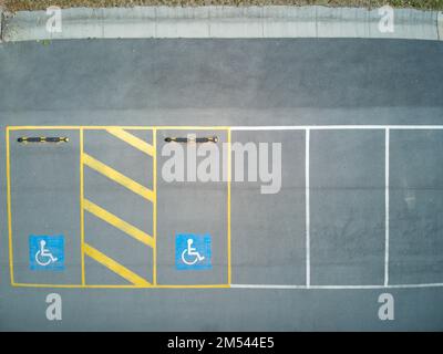 Handicapped parking space aerial view with yellow lines and asphalt texture showing disabled blue badge. Stock Photo