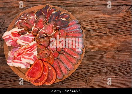 Close up of assorted sliced dry-cured meat on the wooden plate background Stock Photo