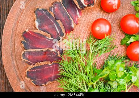 Close up of assorted sliced dry-cured meat on the wooden plate background Stock Photo