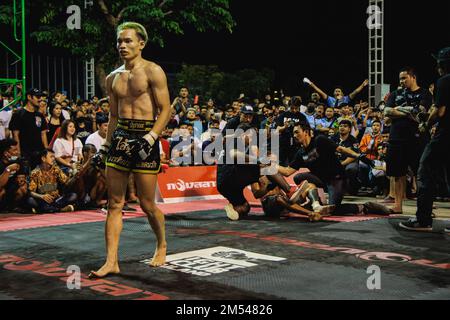 Yern Joker, famous fighter of The Fight Club Thailand seen walking in front of the audiences during the fight at Bangmot Sport Training Center. Due to the popularly of the Fight Club movie in 1999, Fight Club Thailand started in 2016 and made the community of combat sport enthusiast via Facebook group then gathered people and held the underground fighting ring. The rules of this underground fighting ring are simply based on 'don't make enemy make friends'. The subtly detail include; don't challenge the fight outside the fight club, don't make a matching by yourself, don't make enemy, If you ar Stock Photo