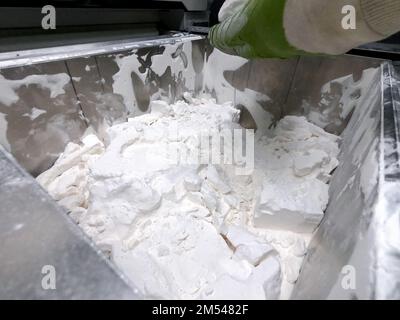 Mane taking out models from white polyamide powder in working chamber of 3D printer, cleaning and removes powder. Process of creating model on powder 3D printer. Multi Jet Fusion MJF. Worker hands Stock Photo