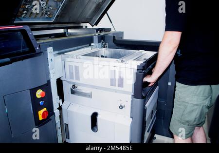 The worker moves the working camera of the 3D printer into the 3D printer. Large industrial 3D printer printing with polyamide powder in a production laboratory. Multi Jet Fusion. Industrial equipment Stock Photo