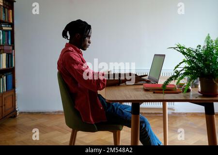 Successful professional African American man at work desk with laptop and typing text for blog Stock Photo