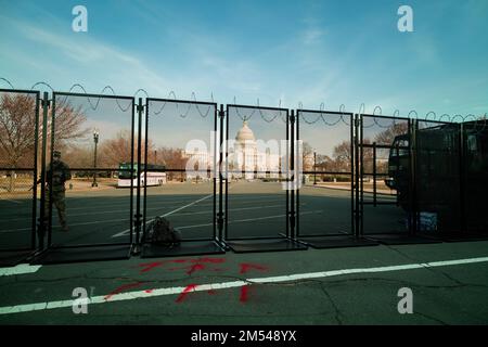 A National Guard soldier stands guard at the U.S. Capitol building in Washington, DC. at sunset, fortified behind a metal fence topped with razor wire Stock Photo