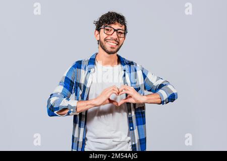 Teenage guy making heart shape with hands isolated. Happy man making heart shape with hands isolated. Person putting hands together in a heart shape Stock Photo